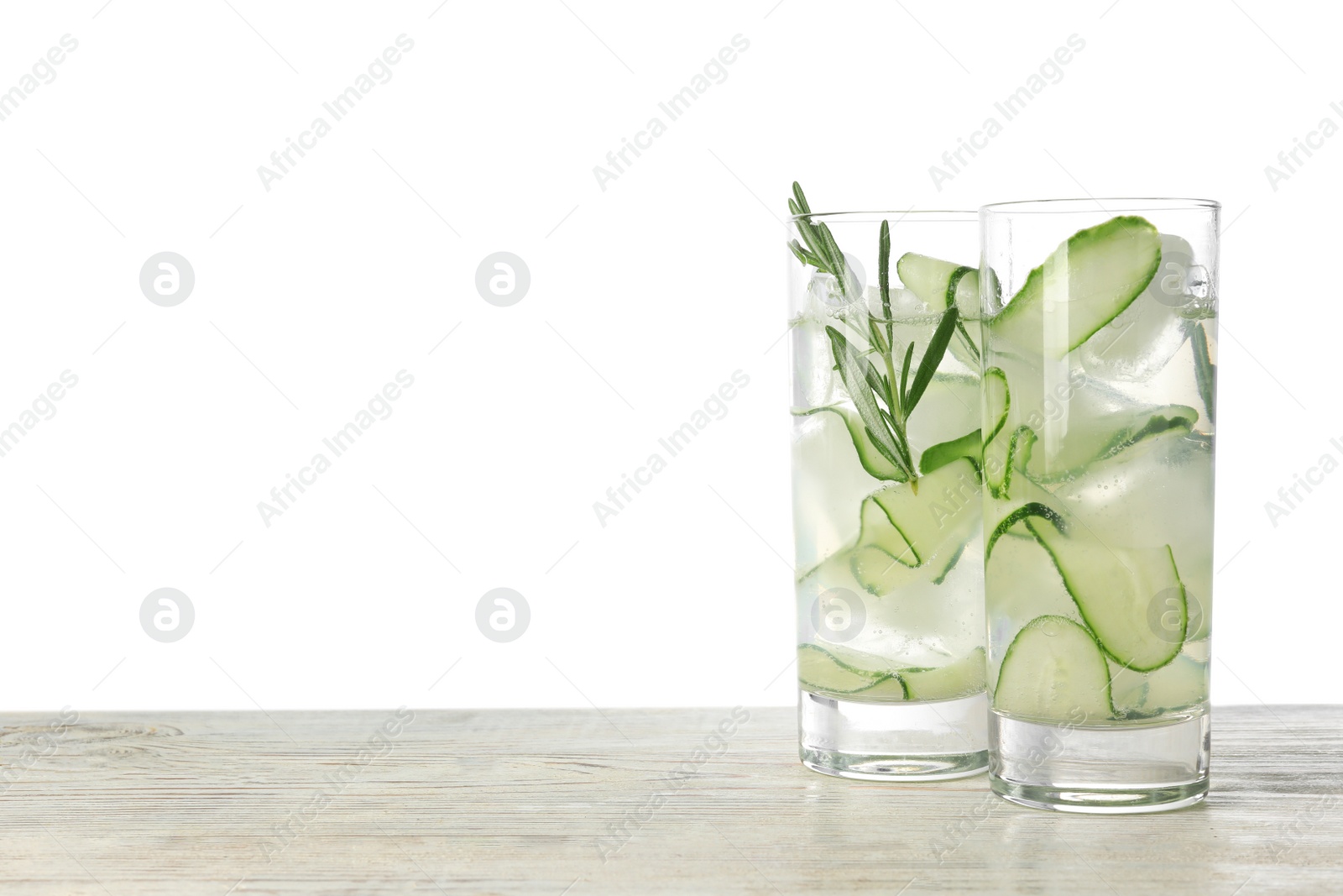 Photo of Glasses of refreshing cucumber lemonade on wooden table against white background, space for text. Summer drink
