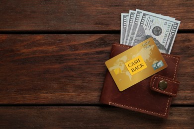 Photo of Dollar banknotes in wallet and credit card on wooden background, top view with space for text. Cashback concept