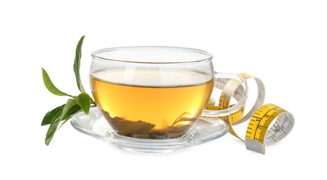 Photo of Glass cup of diet herbal tea, green leaves and measuring tape on white background