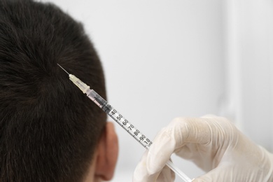 Photo of Man with hair loss problem receiving injection in salon, closeup