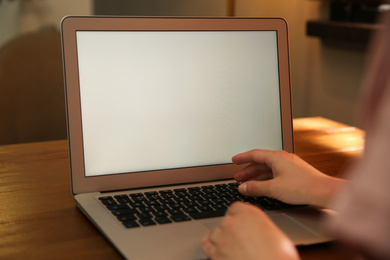 Photo of Woman working with modern laptop at wooden table, closeup. Space for design