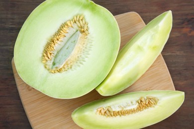 Cut tasty ripe melons on wooden table, above view