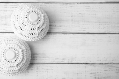 Photo of Laundry dryer balls on white wooden table, flat lay. Space for text