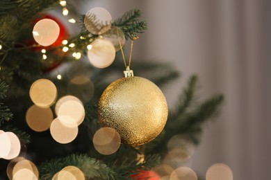 Photo of Christmas tree decorated with festive balls and lights on light background, closeup