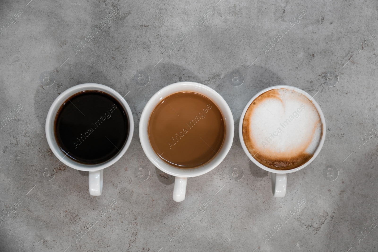 Photo of Cups of fresh aromatic coffee on grey background, top view