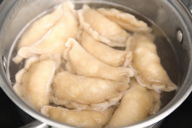 Cooking dumplings (varenyky) with cottage cheese in pot, closeup