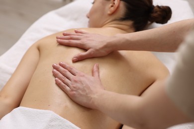 Woman receiving back massage on couch in spa salon, closeup