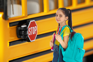 Image of Girl with backpack near yellow school bus. Transport for students