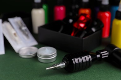 Tattoo machine and tools on dark green table, closeup