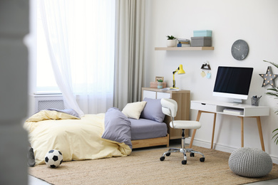 Stylish teenager's room interior with comfortable bed and workplace