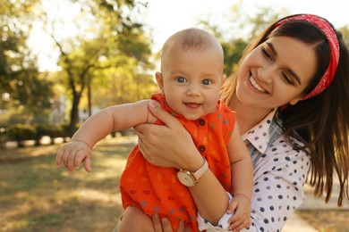 Young mother with her cute baby in park on sunny day