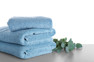 Photo of Fresh towels and eucalyptus branches on light grey table against white background