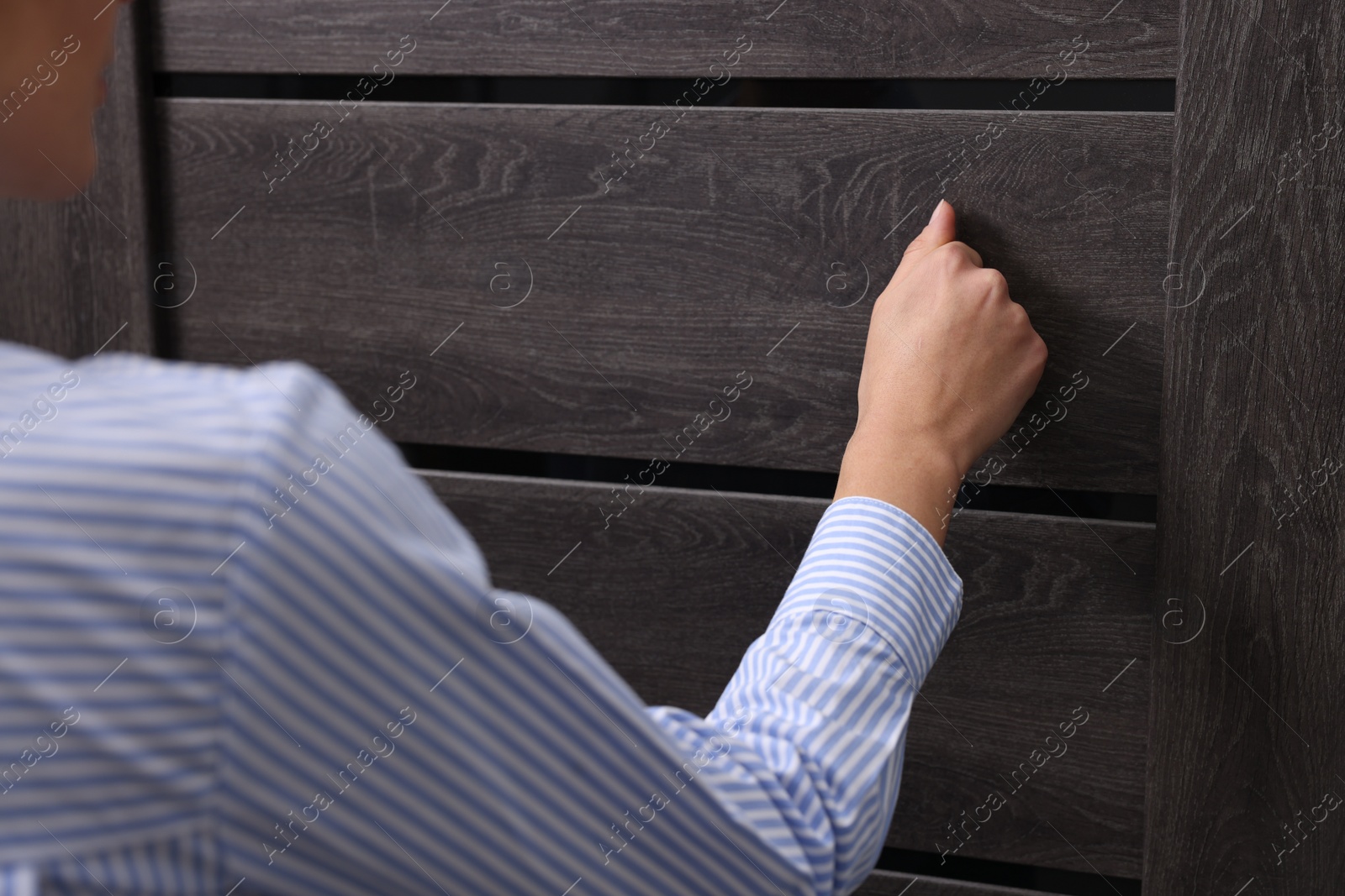 Photo of Woman knocking on door indoors, closeup view