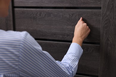 Photo of Woman knocking on door indoors, closeup view