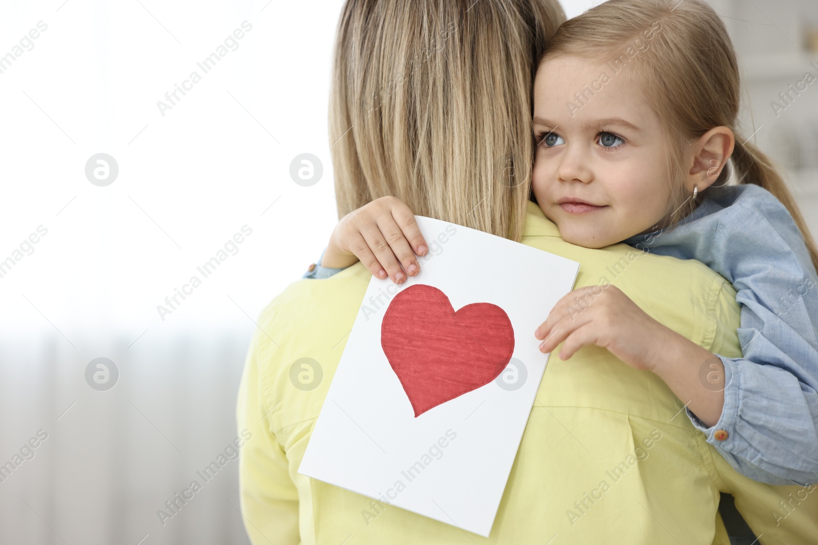 Photo of Little daughter congratulating her mom with greeting card at home, space for text. Happy Mother's Day