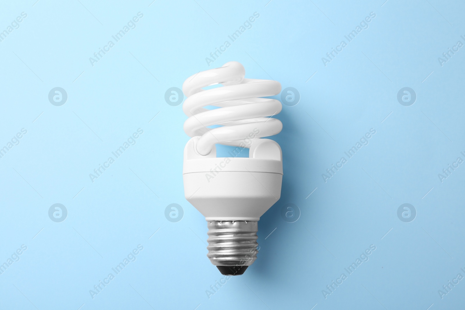 Photo of New modern lamp bulb on light blue background, top view