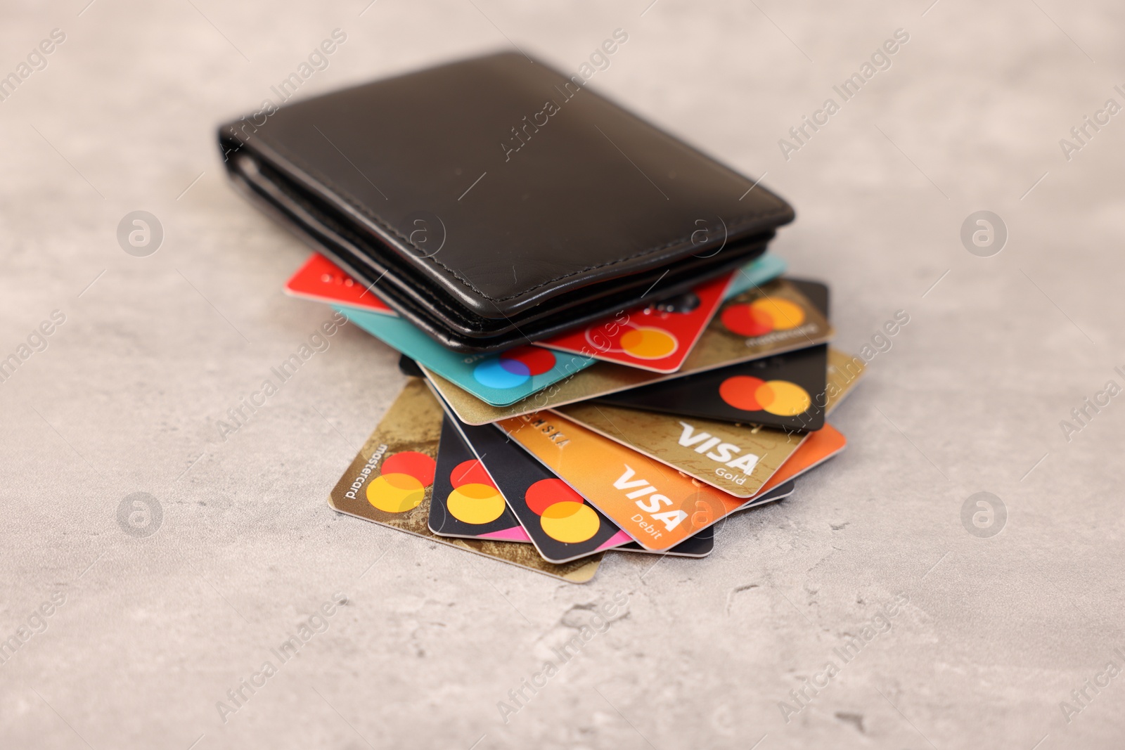 Photo of LEIDEN, NETHERLANDS - MARCH 07, 2024: Bank cards of Visa and Mastercard payment systems in leather wallet on light grey table