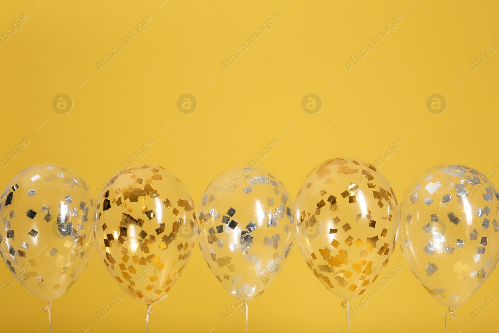 Photo of Bright balloons with ribbons on color background. Space for text