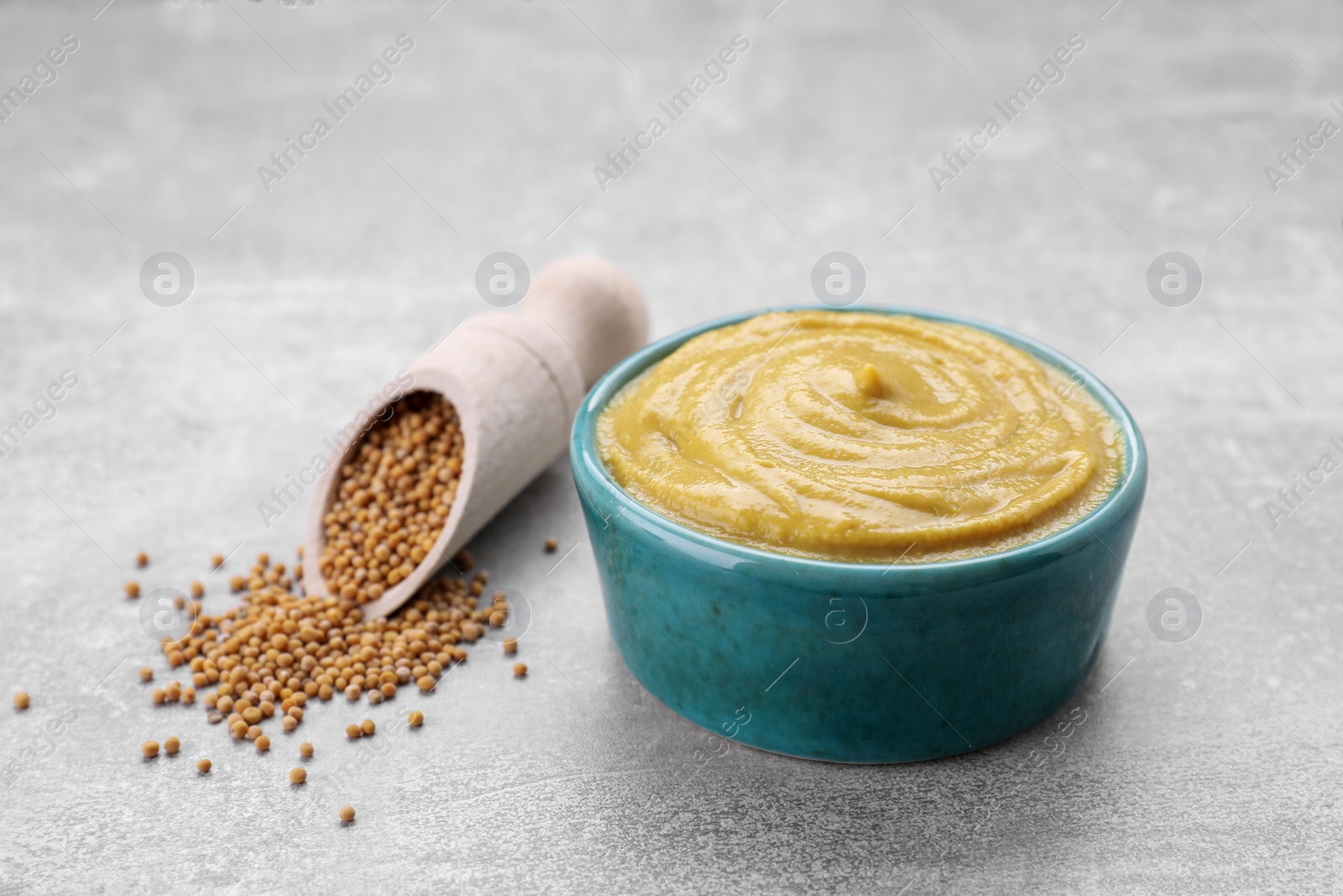 Photo of Bowl with delicious mustard and seeds on light grey table