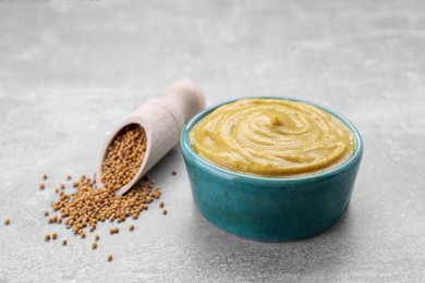 Bowl with delicious mustard and seeds on light grey table