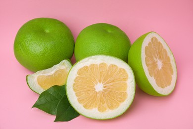 Photo of Tasty whole and cut sweeties on pink background