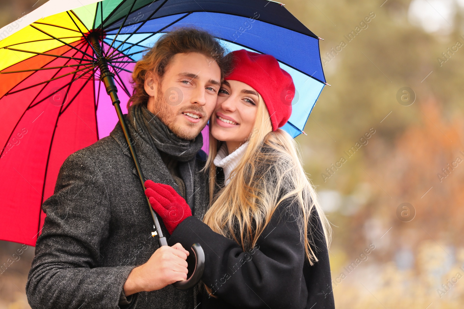 Photo of Young romantic couple with umbrella outdoors on autumn day