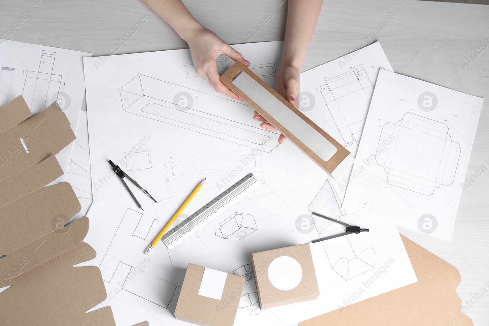 Photo of Woman creating packaging design at light wooden table, top view