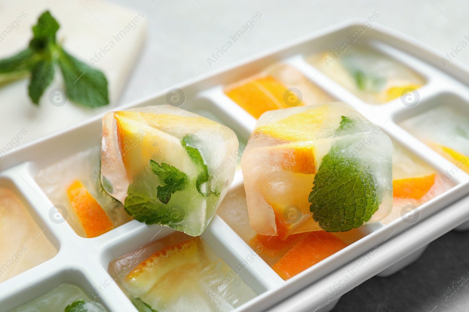 Photo of Ice cubes with orange and mint on light table, closeup