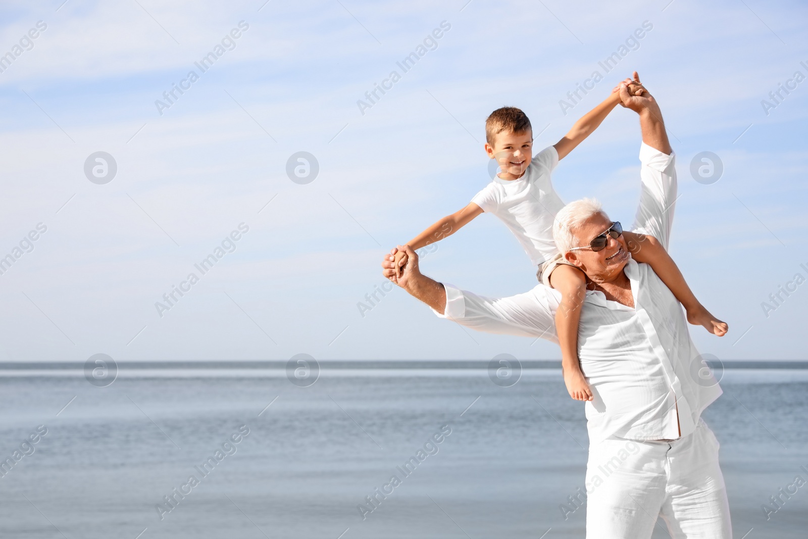 Photo of Cute little boy with grandfather spending time together near sea