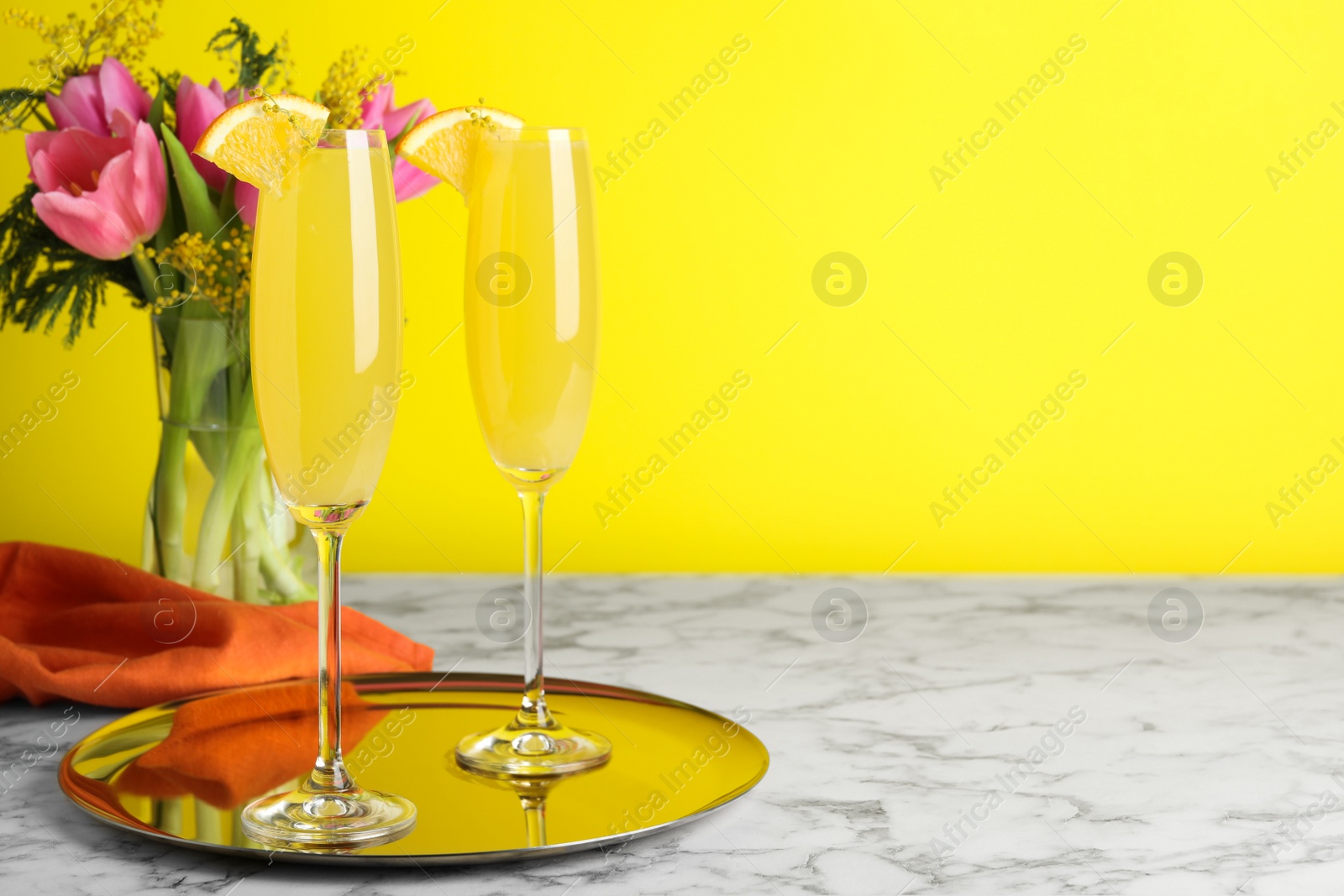Photo of Glasses of Mimosa cocktail with garnish on white marble table. Space for text