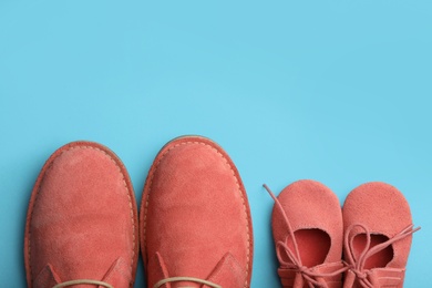 Photo of Big and small coral shoes on light blue background, top view. Space for text