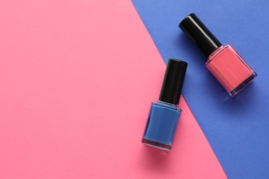 Bright nail polishes in bottles on color background, flat lay. Space for text