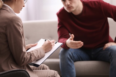 Photo of Psychotherapist working with young man in office, closeup