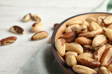 Bowl with tasty Brazil nuts on table, closeup. Space for text