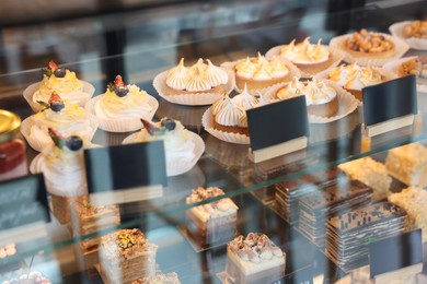 Photo of Different tasty desserts on counter in store