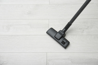 Hoovering floor with modern vacuum cleaner indoors, top view. Space for text