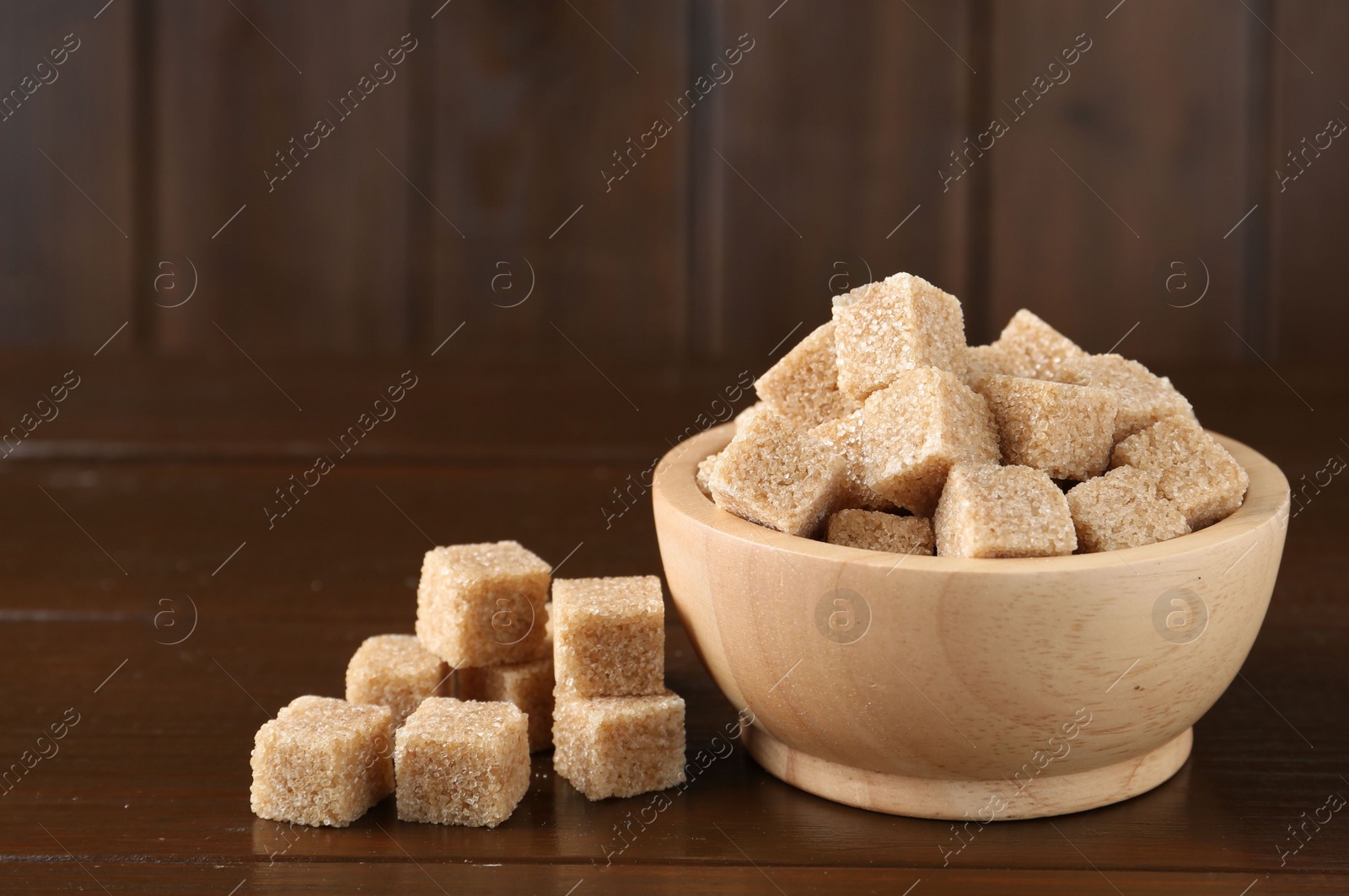 Photo of Brown sugar cubes on wooden table, closeup