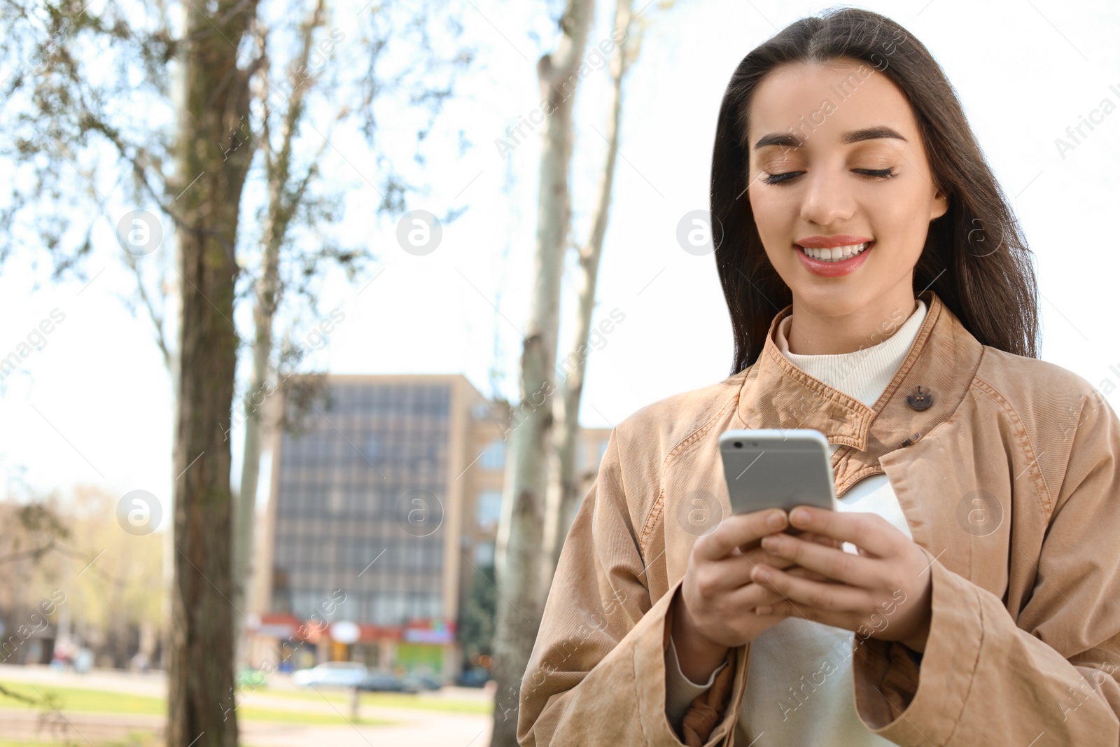 Photo of Young woman using phone outdoors on sunny day