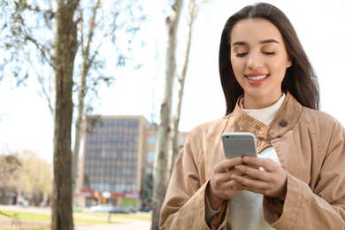 Photo of Young woman using phone outdoors on sunny day