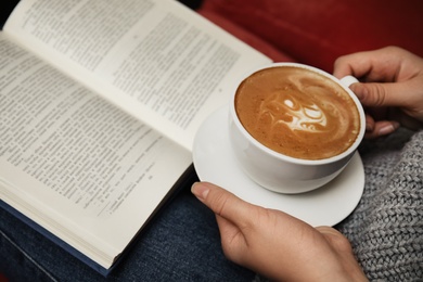 Photo of Woman with cup of coffee reading book, closeup
