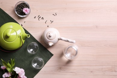 Beautiful traditional tea ceremony set and sakura flowers on wooden table, flat lay. Space for text