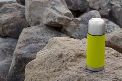 Metallic thermos with hot drink on stone, space for text