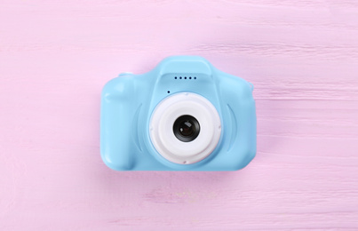 Photo of Light blue toy camera on pink wooden background, top view