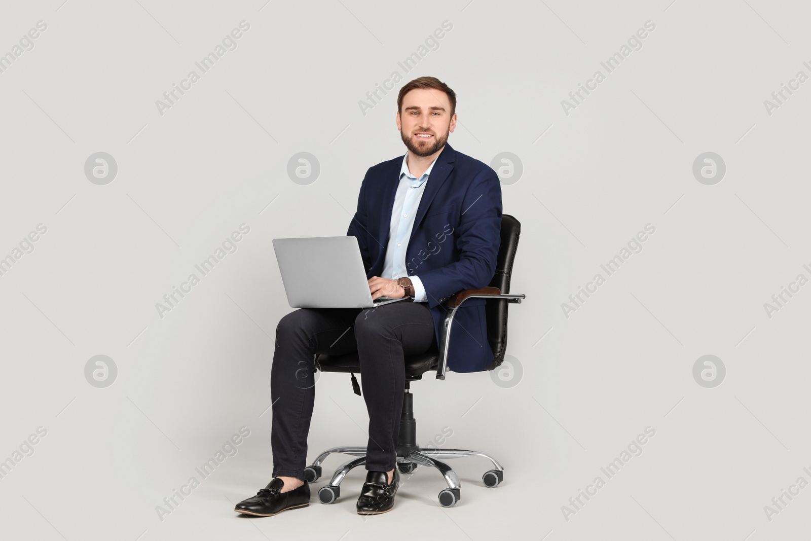 Photo of Young businessman with laptop sitting in comfortable office chair on grey background