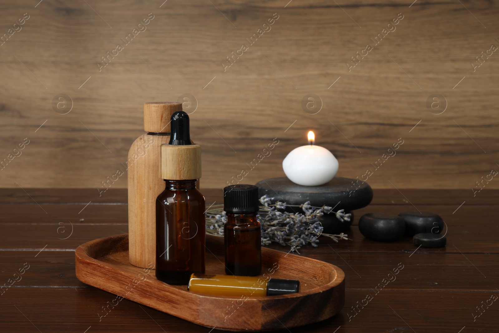 Photo of Aromatherapy products, burning candle and lavender on wooden table