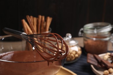Bowl with chocolate cream, whisk and ingredients on table, closeup. Space for text