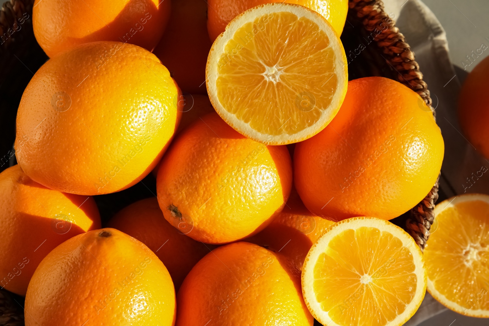 Photo of Fresh juicy oranges in wicker basket on table, top view