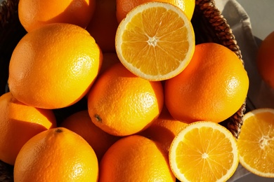 Photo of Fresh juicy oranges in wicker basket on table, top view