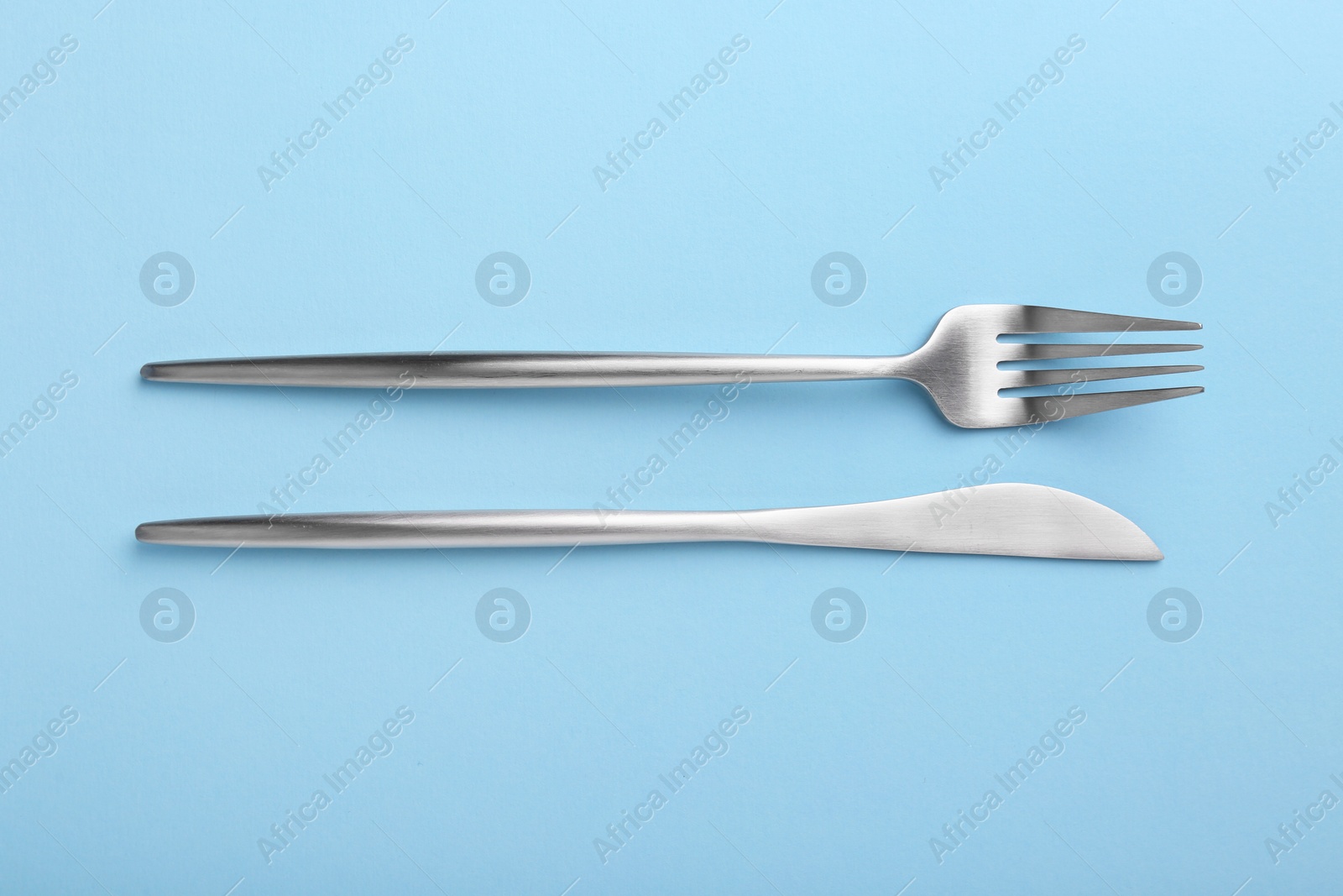 Photo of Stylish cutlery on light blue table, top view