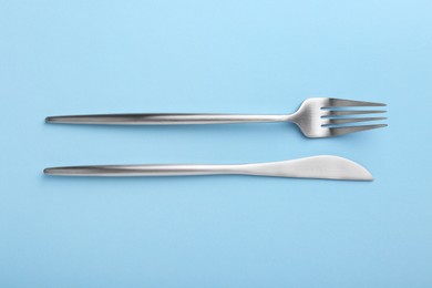 Stylish cutlery on light blue table, top view